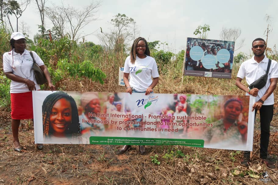 No Limit International Co-Founder Orlyanka Tantchou and two others hold a No Limit International banner that reads: “No Limit International - Promoting sustainable livelihoods by providing land to farm opportunities to communities in need.”